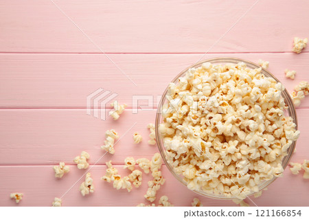 Popcorn in glass bowl on pink wooden background. 121166854