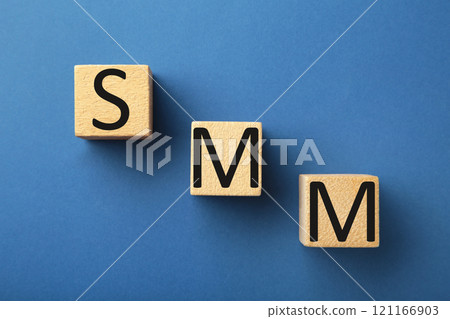 Wooden cubes with word SMM on blue background. Wooden cubes with word SMM on blue background. 121166903