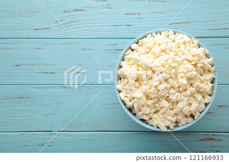 Cottage cheese for breakfast in bowl on blue wooden background. 121166933