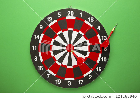 Dart board with red darts on green background. Dart board with red darts on green background. 121166940