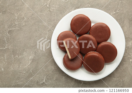 Choco pie chocolate coated snacks in plate on grey background. Choco pie chocolate coated snacks in plate on grey background. 121166950