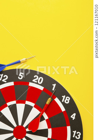 Dart board with darts on yellow background. Vertical photo. 121167010