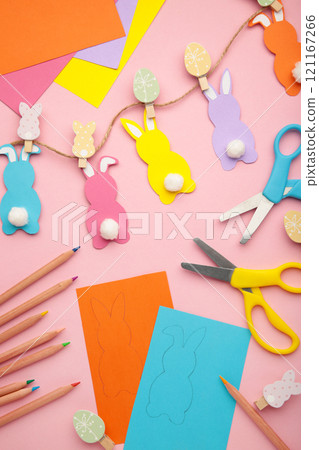 Easter bunnies handmade from colored paper, easy crafts for kids on a pink background. Easter bunnies handmade from colored paper, easy crafts for kids on a pink background. 121167266