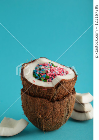 Coconut with rainbow sprinkles inside on blue background. 121167298