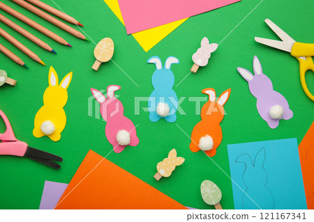Easter bunnies handmade from colored paper, easy crafts for kids on a green background. Easter bunnies handmade from colored paper, easy crafts for kids on a green background. 121167341