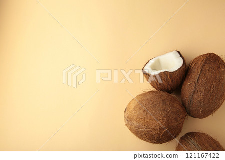 Coconut on a beige background. Halves and whole coconuts. Top view. 121167422