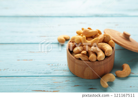 Cashew nuts on wooden bowl on blue background. Top view. 121167511