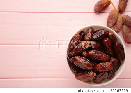 White bowl of dried dates on pink background. White bowl of dried dates on pink background. 121167519