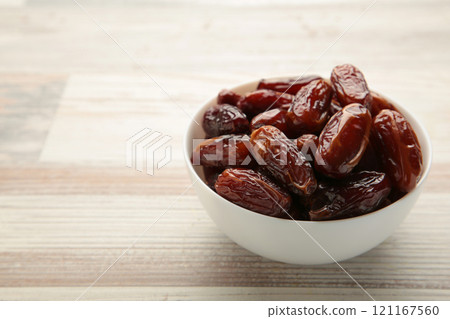 White bowl of dried dates on grey background. 121167560