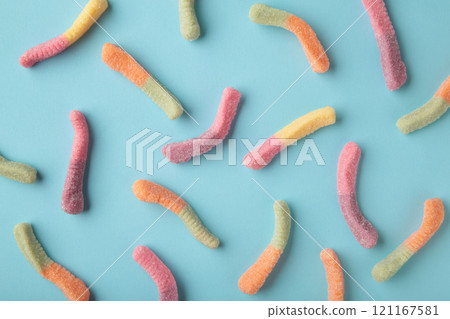 Top view of colorful gummy jelly worm candies on blue background. 121167581