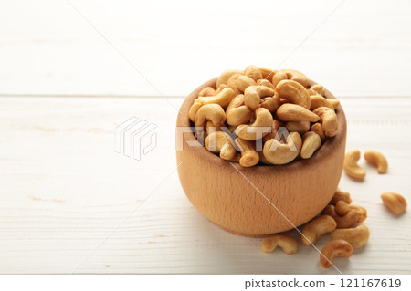 Cashew nuts on wooden bowl on white background. Top view. Cashew nuts on wooden bowl on white background. Top view. 121167619