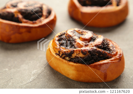 Bun with poppy seeds on grey background. Bun with poppy seeds on grey background. 121167620