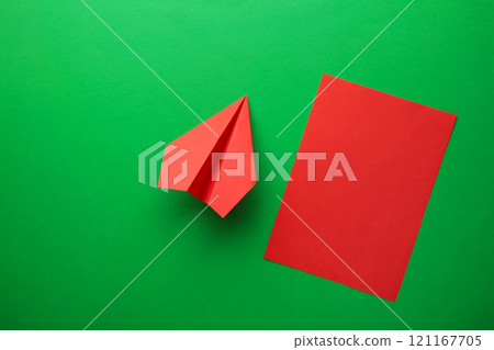 Flat lay of red paper plane and blank paper on green background. 121167705