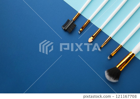 Various makeup brushes on blue and dark blue background with copy space. Various makeup brushes on blue and dark blue background with copy space. 121167708
