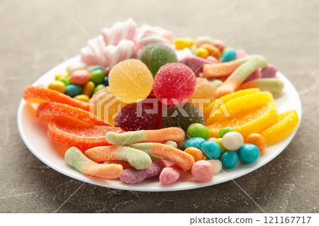 Colorful candies lollipops and jelly in plate on grey background. Top view. Sweets with copy space Colorful candies lollipops and jelly in plate on grey background. Top view. Sweets with copy space 121167717
