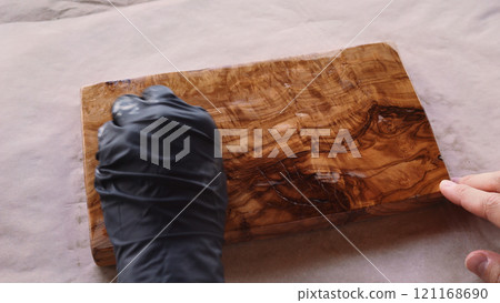 woodworker applying oil finish to olive wood board from above 121168690