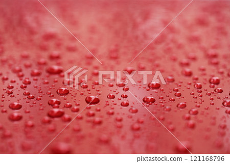Closeup rain drops on red car with hydrophobic coating 121168796