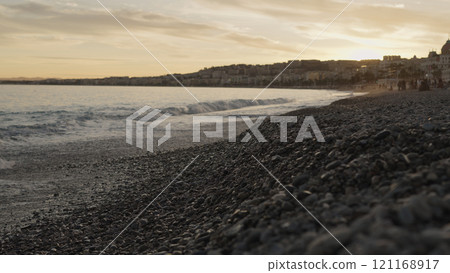 Low angle shot of sunset on a pebble beach of Nice 121168917