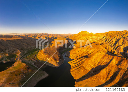 Panoramic aerial view on picturesque Azat reservoir and Eranos mountain at bright sunny evning sunset. Lake with blue water in arid area and Yeranos mountains range. Beautiful landscape. Armenia. Panoramic aerial view on picturesque Azat reservoir and Eranos mountain at bright sunny evning sunset. Lake with blue water in arid area and Yeranos mountains range. Beautiful landscape. Armenia. 121169183
