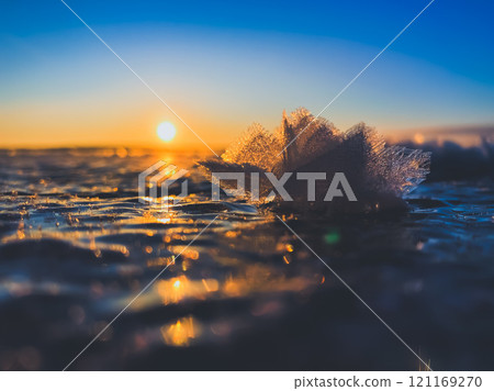 Frosty air and frozen lake surface in a beautiful sunset landscape. Beautiful ice shapes and sunlight. Photo from Sotkamo, Finland. 121169270