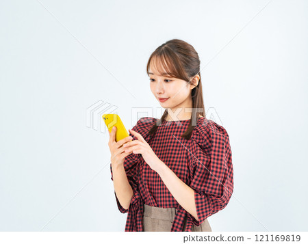 A woman in casual wear looking at her smartphone A woman in casual wear looking at her smartphone 121169819