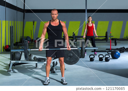 gym with weight lifting bar workout man and woman 121170085