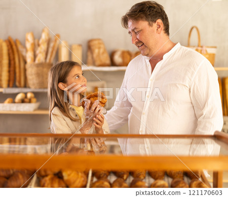 Dad and daughter customers holding loaf of bread and baguettes with hands in disposable gloves. 121170603