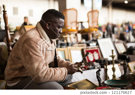 Man chooses antiques at a flea market Man chooses antiques at a flea market 121170627