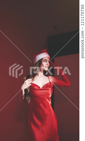 Sexy happy woman with long hair in New Year's hat and red dress posing on white background at New Year's party style photo shoot Sexy happy woman with long hair in New Year's hat and red dress posing on white background at New Year's party style photo shoot 121170788
