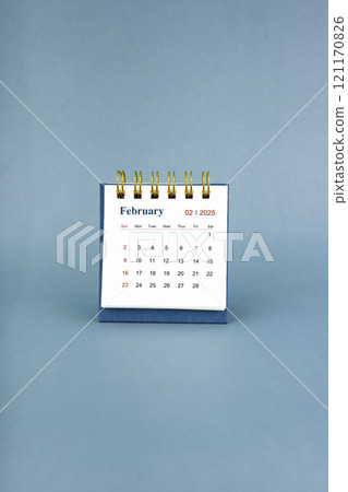 February 2025 white desk calendar on blue background. 121170826