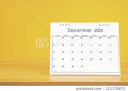 December 2025, Monthly desk calendar for 2025 year on wooden table on yellow background. 121170873
