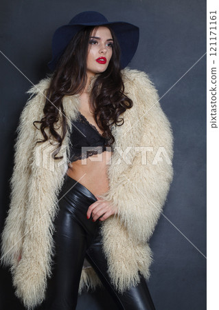 Standing woman with red lips make-up and long wavy hair wearing blue hat  121171161