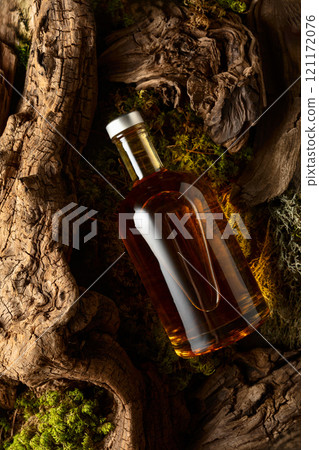 Bottle of strong alcoholic drink, old snags, and moss. 121172076