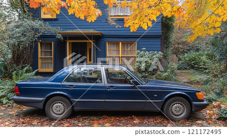 Classic blue sedan parked outside a charming blue house surrounded by autumn leaves 121172495