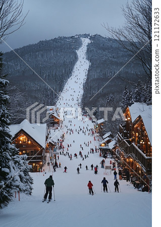 Twilight at a bustling ski resort with skiers enjoying the slopes during the winter season 121172633