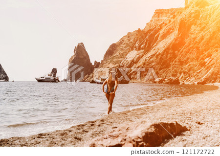 Woman travel summer sea. A happy tourist in a blue bikini enjoying the scenic view of the sea and volcanic mountains while taking pictures to capture the memories of her travel adventure. 121172722