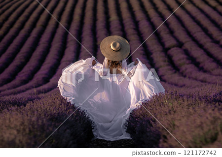 Lavender Fields Woman Dress France: A woman in a white dress and hat enjoys a picturesque lavender field in Provence, France, during summer. Lavender Fields Woman Dress France: A woman in a white dress and hat enjoys a picturesque lavender field in Provence, France, during summer. 121172742