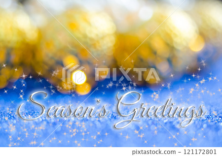 Season's Greetings text with white stars and blurred golden Christmas balls on blue background. Christmas and Holiday season 121172801