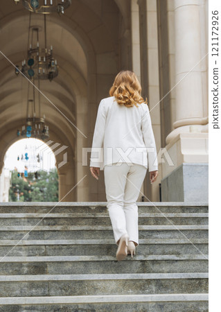 Woman White Suit Stairs - Walking up the stairs of a grand building in a white suit. 121172926