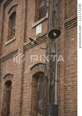 Red brick warehouse, wooden utility pole and bare bulb outdoor light 2 121173289