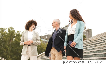Confident business coworkers discussing near stairs in city Confident business coworkers discussing near stairs in city 121174125