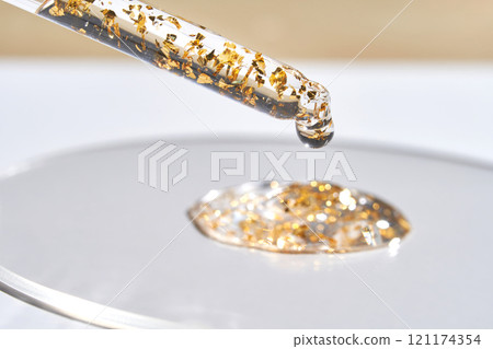 Luxury skincare serum with gold flakes in glass dropper on white surface Luxury skincare serum with gold flakes in glass dropper on white surface 121174354
