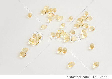 Scattered gel capsules on white background highlighting health and wellness 121174358