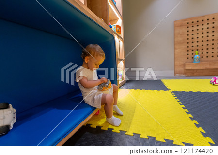 Child playing with a toy in colorful playroom. Concept of early childhood learning and creativity Child playing with a toy in colorful playroom. Concept of early childhood learning and creativity 121174420