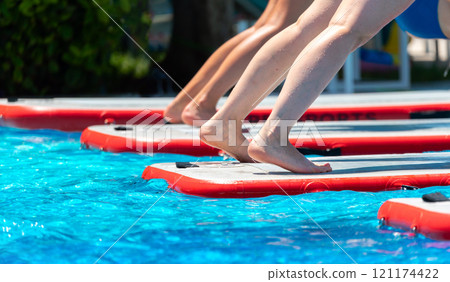 Group performing yoga on paddleboards in a sunny pool. Concept of tropical wellness and fitness 121174422