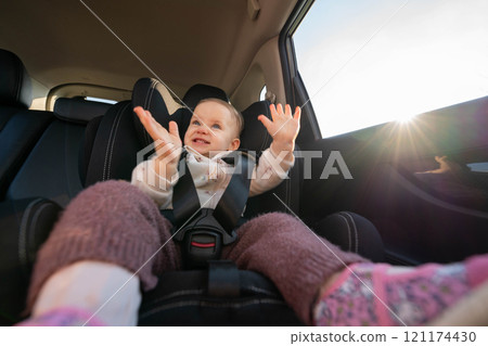 Happy baby clapping hands in car seat during road trip. Concept of safe travel and joyful moments for young children 121174430