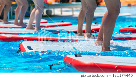 Splashing feet on paddleboards in a sunny pool. Concept of tropical fitness and fun outdoor activities 121174440