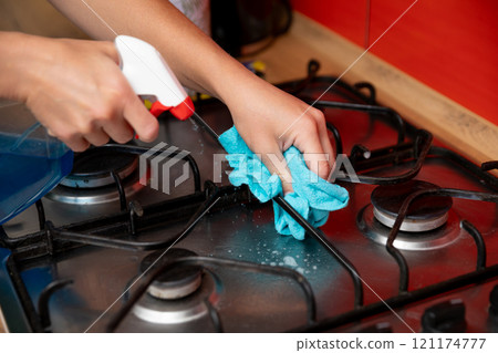 Taking Care to Clean the Kitchen Stove Surface Thoroughly and With Attention to Detail 121174777