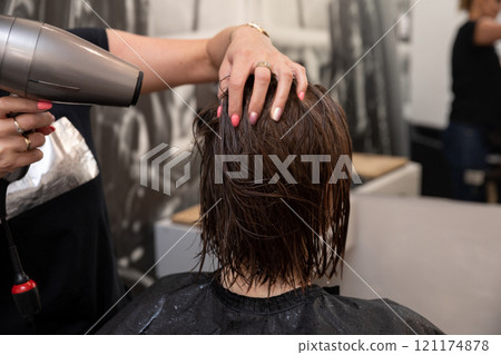 A skilled hairdresser demonstrates the artistry of styling hair using a blow dryer expertly A skilled hairdresser demonstrates the artistry of styling hair using a blow dryer expertly 121174878