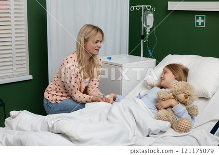 A nurturing mother and her child share a moment of comfort and affection in a hospital room A nurturing mother and her child share a moment of comfort and affection in a hospital room 121175079